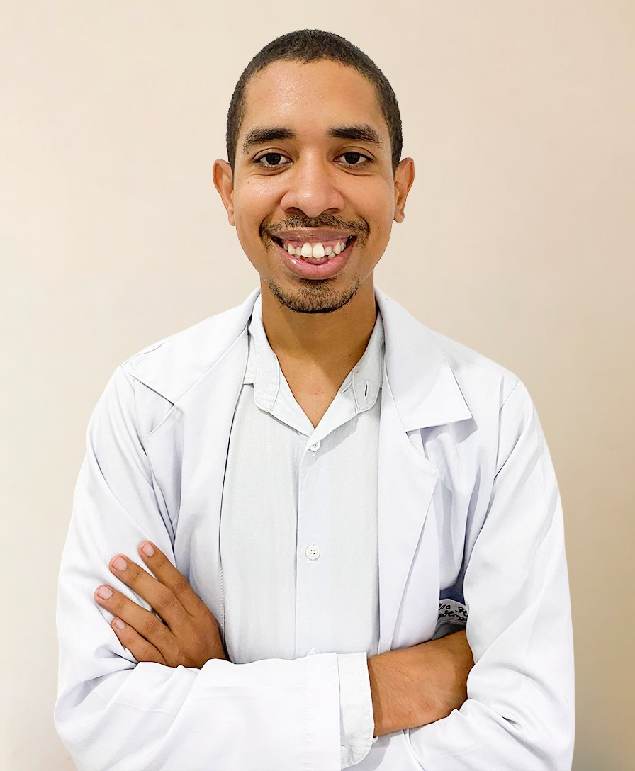 Carlos, naturólogo clínico, de jaleco branco, de braços cruzados e sorrindo